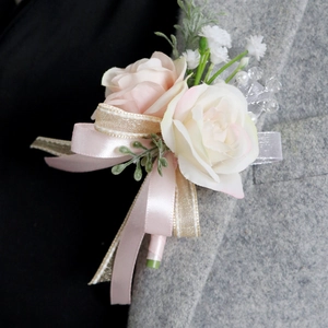 Fiore all'occhiello rosa e crema su bavero grigio con dettaglio nastro di raso