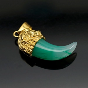 Macro detail of gold plated lion head carving with translucent green resin wolf tooth pendant