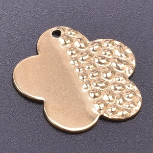 Macro shot of 18k gold-plated clover pendant with hammered texture and smooth finish
