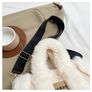 Detail of soft cream faux fur tote bag with black strap and golden metal hardware