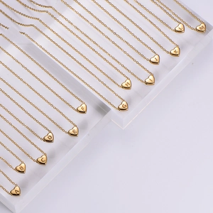 18K gold plated heart initial necklaces displayed on a clear jewelry stand