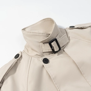 Gros plan du col d'un trench-coat beige avec boucle noire réglable et pattes d'épaule