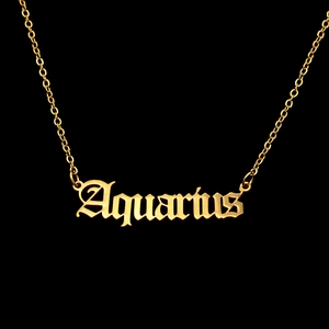 Macro detail of golden Aquarius gothic letter pendant on a delicate O-chain necklace