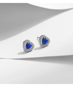 Détail de boucles d'oreilles cœur en opale bleue avec halo de zircones et monture argent