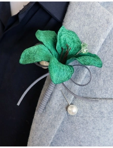 Macro detail of handmade green fabric flower boutonniere with pearl pin on tweed suit