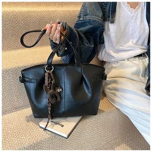 Detail of black pleated PU leather tote bag featuring a cute cat charm on the handle
