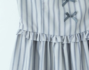 Close-up detail of blue-grey striped dress featuring pleated texture and bow knot