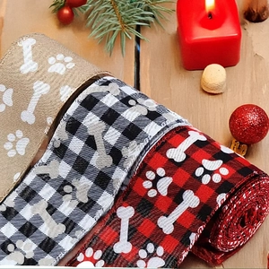 Close-up of three rolls of Christmas buffalo plaid ribbons with paw and bone prints