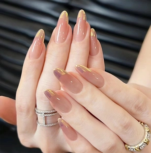 Detailed view of long almond press-on nails with nude pink base and aurora gold French tips
