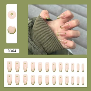 French tip press-on nails set with blush pink base and green dot detail in coffin shape