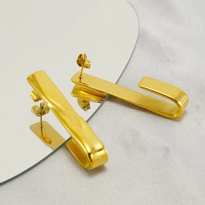 Minimalist gold stainless steel curved bar drop earrings shown on a reflective surface
