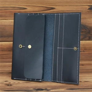Detail of vintage navy blue leather wallet with white stitching and brass snap button