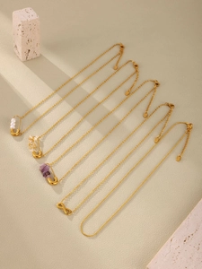 Gros plan détaillé de cinq colliers dorés avec pendentifs en pierre naturelle et perle