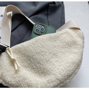 Close-up of white plush crossbody bag with soft faux fur texture and green phone inside