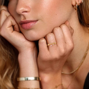 Gold heart ring with pink zircon pendants on a model with matching jewelry