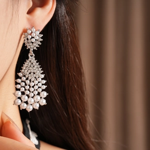 Close-up of silver chandelier earrings with pearls and crystals worn by a female model