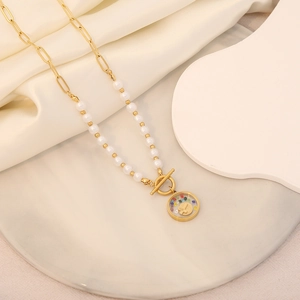 Detail of gold chain necklace featuring pearls and a cross pendant on white silk