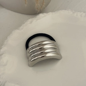Close-up of elegant silver metallic layered hair tie on decorative ceramic plate