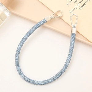 Blue denim fabric wristlet strap with silver metal lobster clasps on a beige tray