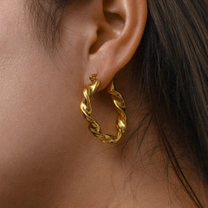 Gros plan des boucles d'oreilles créoles torsadées plaquées or 18 carats sur le mannequin