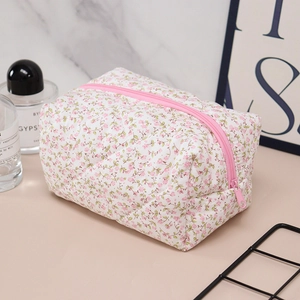 Detail of floral makeup bag with pink zipper on marble surface in a lifestyle setting