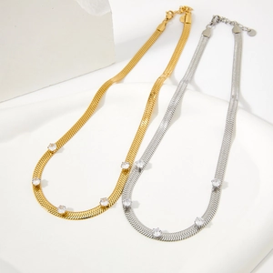 Eleganti collane a catena serpente oro e argento con zirconi lucenti su pietra bianca fondo