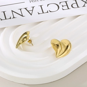 Macro detail of golden 18K gold-plated heart stud earrings with wavy metal texture