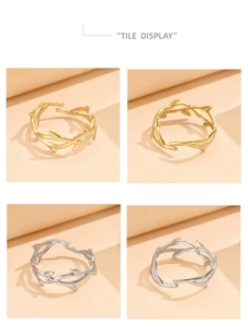 Detail view of thorn and leaf branch rings in gold and silver finishes on beige surface