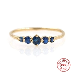 Detailed close-up of 925 sterling silver ring with five round blue gemstones and gold plating