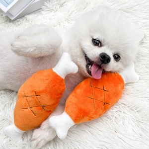 Plush squeaky chicken leg dog toy with soft orange fabric and white bone detail
