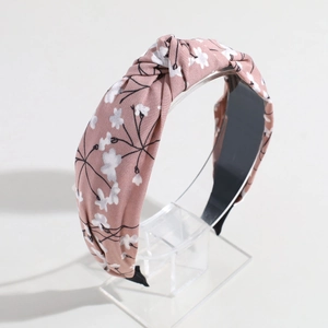 Detailed view of pink floral knotted headband on a transparent display stand