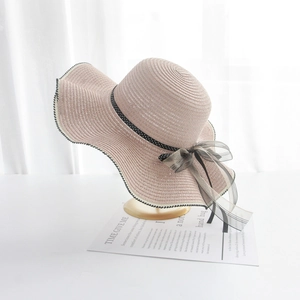 Detail of pink wide-brim straw hat with polka dot ribbon and black bow on display stand