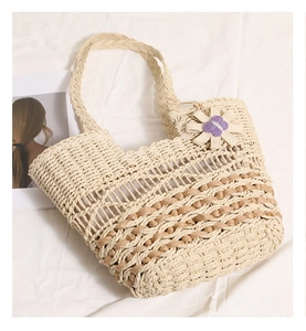 Close-up of hollow straw woven bag with purple flower detail on white background