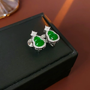 Macro shot of green gourd-shaped zircon earrings on a black leather jewelry box