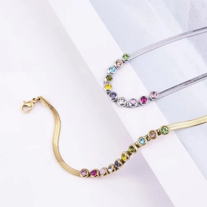 Detail of gold and silver blade chains with colorful rhinestones on a white geometric stage