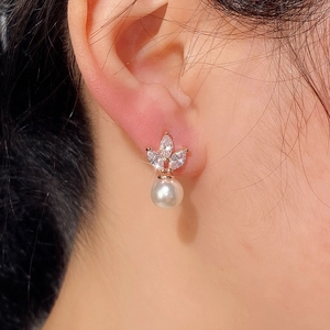 Detail of horse-eye zircon earrings with round pearl on model earlobe