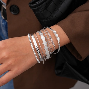 Close-up of stacked silver bracelets set with bohemian patterns and cubic zirconia charms