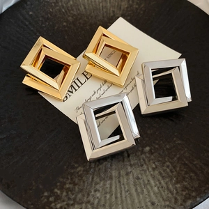 Detail of geometric rhombus earrings in gold and silver finish on a display card