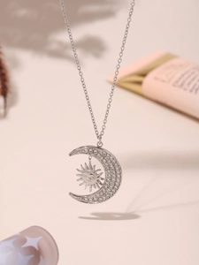 Detailed view of silver sun and crescent moon necklace set with sparkling zircon crystals