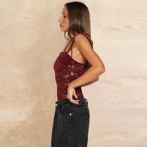 Detail of burgundy lace bodysuit with thin straps paired with high waist black jeans