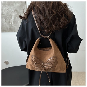 Détail du sac bandoulière en daim avec patchwork papillon et détails de laçage