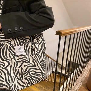 Detail of zebra print corduroy tote bag showing the texture and brand patch on shoulder strap