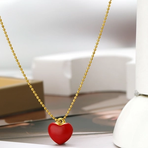 Macro shot of a red enamel heart pendant on a gold ball chain for DIY jewelry