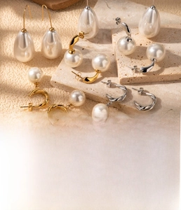 Macro detail of French vintage C-shaped pearl earrings in gold and steel finish