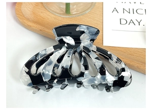 Macro detail of elegant black and white marble acetate hair claw clip with hollow design
