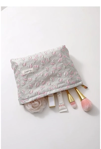 Detailed view of a floral embroidered cosmetic bag with brushes and makeup accessories