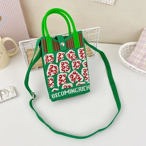 Detail of green knit crossbody bag with red lucky character and adjustable strap