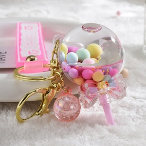 Detail of liquid sand lollipop keychain with pink bow, bell and colorful beads