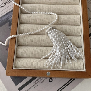 Detail view of pearl tassel necklace with silver accents on a soft velvet jewelry tray