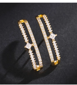 Détail macro de boucles d'oreilles géométriques dorées à deux couches avec zircon carré